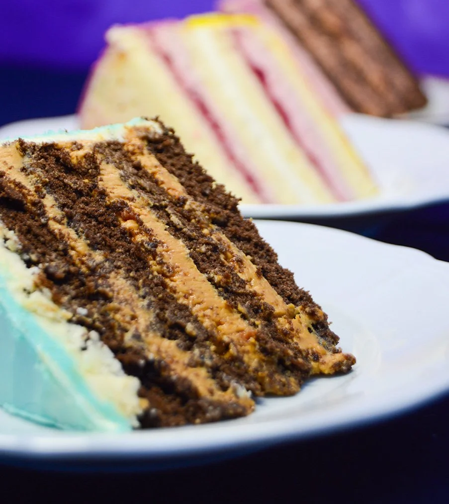 Imagen de detalle del interior de la tarta de dulce de leche con cacahuetes caramelizados en forma de porción. Se puede ver que la tarta tiene cuatro bizcochos finos esponjosos y tres rellenos cremosos y abundantes artesanos de dulce de leche con cacahuetes caramelizados.